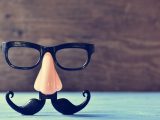 a fake mustache, nose and eyeglasses on a rustic blue wooden surface